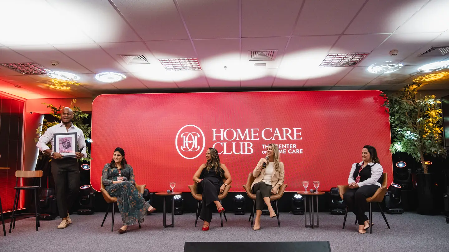 Membros do Home Care Club no palco durante encontro presencial